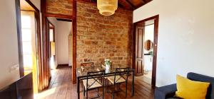 a living room with a table and a brick wall at Lina House Garden, BBQ & Outdoor Dining in Puntagorda