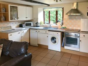 a kitchen with a washing machine and a microwave at Colombo Cottage in Uplyme