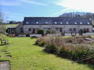 a large stone house with a lawn in front of it at Colombo Cottage in Uplyme