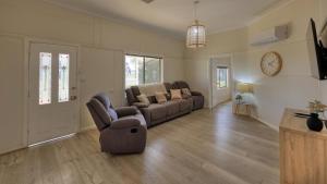 a living room with a couch and a clock on the wall at Castlereagh Lodge Motel in Coonamble