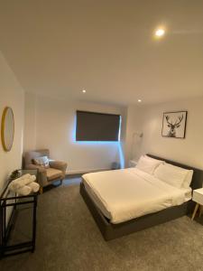 a bedroom with a bed and a chair and a television at SECC&HYDRO BeAUTIFUL 2BR APARTMENT WITH FREE PARKING in Glasgow