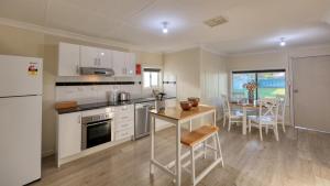 a kitchen with white appliances and a table and a dining room at Castlereagh Lodge Motel in Coonamble