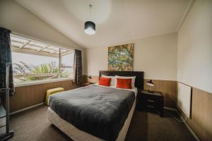 a bedroom with a bed with orange pillows and a window at Lakes Edge Holiday Park in Lake Tekapo
