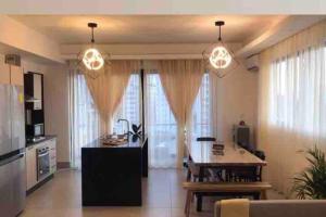 a living room with a table and a kitchen with windows at Hermoso apartamento de dos dormitorios in Santiago de los Caballeros