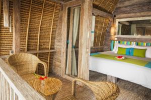 een slaapkamer met een bed en stoelen in een kamer bij Hai Tide Beach Resort in Nusa Lembongan