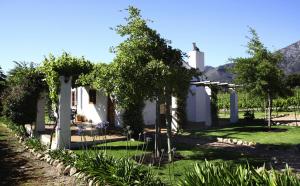 a house with a garden and a cross in the background at Bo La Motte Farm Cottages in Franschhoek