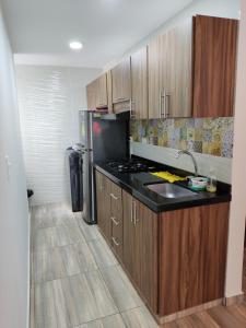 cocina con armarios de madera y encimera negra en Hermoso y Cómodo Apartamento--Excelente Ubicación en San Gil