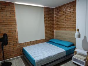 Schlafzimmer mit Ziegelwand und Bett in der Unterkunft Hermoso y Cómodo Apartamento--Excelente Ubicación in San Gil