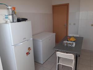 a kitchen with a white refrigerator and a table with bananas at Lugar calmo na cidade sol 
