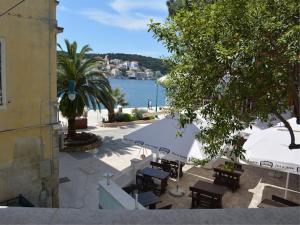 un patio con tavoli e ombrelloni accanto all'acqua di Apartments Mandarina a Mali Lošinj (Lussinpiccolo)