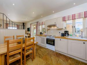 Castlemans Stables East في Sedlescombe: مطبخ بدولاب بيضاء وطاولة خشبية