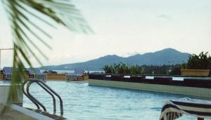 a swimming pool with chairs and mountains in the background at Hotel Gran Puri Manado in Manado