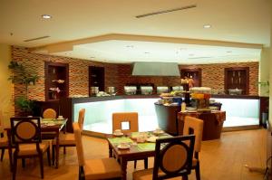 a dining room with tables and chairs and a kitchen at Hotel Gran Puri Manado in Manado