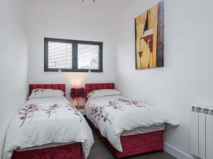 two beds in a room with white walls at Sunnyside Lodge in Glastonbury