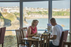 a man and woman sitting at a table in front of a boat at Great Western in Newquay