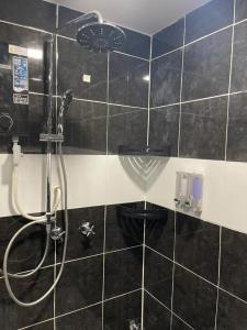 ein schwarz gefliestes Bad mit einer Dusche und einem WC in der Unterkunft Marina View Villas Pinnacle Guest House in Port Dickson