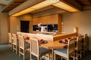 a chef in a kitchen with a table and chairs at Jodogahama Park Hotel in Miyako