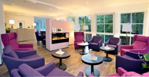 a living room with purple chairs and tables and windows at Hotel Bleske im Spreewald in Burg