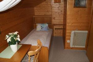 Habitación pequeña con cama, escritorio y mesa. en Gästehaus Ferienwohnungen LACKNER, en Rennweg