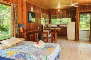 a bedroom with a bed and a kitchen with a refrigerator at Aore Hibiscus Retreat in Aimbuei Bay