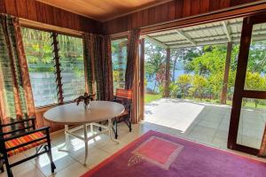 ein Esszimmer mit einem Tisch und einem großen Fenster in der Unterkunft Aore Hibiscus Retreat in Aimbuei Bay