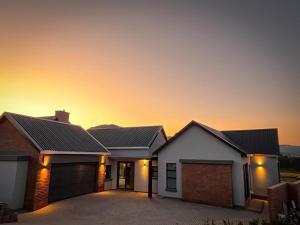 a house with a sunset in the background at The Big Easy Rest at Highland Gate Golf & Trout in Dullstroom