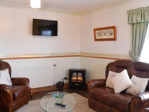 a living room with two leather chairs and a table at West Tannacrieff in Stewarton