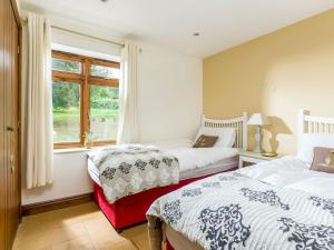 a bedroom with two beds and a window at Campden Barn in Chipping Campden