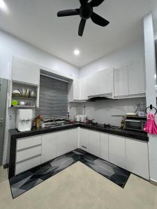 a kitchen with white cabinets and a ceiling fan at Homestay SJTM in Cukai