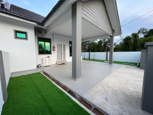 a patio with green grass in front of a house at Homestay SJTM in Cukai