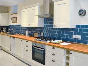 a kitchen with white cabinets and blue tiles on the wall at Hawkins in Dartmouth