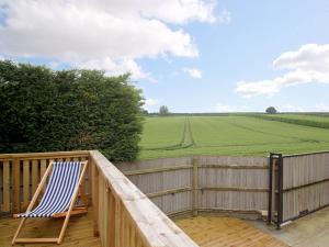 a deck with a chair and a view of a field at Kentish Barn Retreat in Chilham