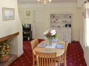 a dining room with a table with flowers on it at Forge Cottage in Happisburgh