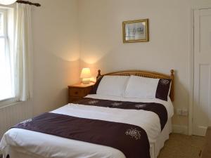 a bedroom with a bed and a lamp on a table at Forge Cottage in Happisburgh