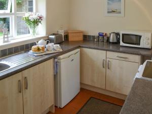 a kitchen with a sink and a microwave at Forge Cottage in Happisburgh