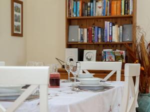 a table with plates and wine glasses and a book shelf at The Bothy At Fordcombe in Speldhurst
