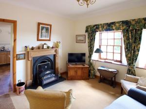 a living room with a fireplace and a tv at Conheath Gatelodge Cottage in Kingholm Quay