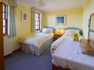 Duas camas num quarto com paredes amarelas e janelas em Conheath Gatelodge Cottage em Kingholm Quay