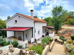 ein weißes Haus mit einem roten Dach und einem Garten in der Unterkunft IVA apartments in Šilo