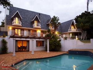 a large house with a swimming pool in front of it at Dark Chocolate Guest House in Durbanville