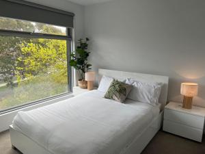 a white bed in a room with a large window at Centrepoint Units Heidelberg in Melbourne