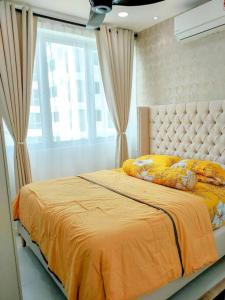 a bedroom with a bed with an orange comforter and a window at NZ Homestay Metrocity Square in Kuching