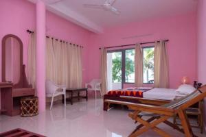 a bedroom with pink walls and a bed and a desk at Orchid Lake View Homestay in Alleppey