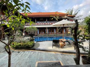 a swimming pool with an umbrella and a house at Mikuk Cottages Canggu in Canggu