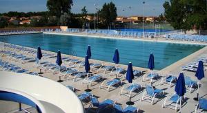 - une piscine avec des chaises et des parasols bleus dans l'établissement Chez Laure , Odalys l Elysée, au Grau-du-Roi