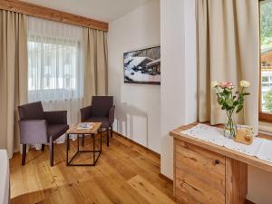 a living room with two chairs and a table with flowers at Hotel Sonnhof in Neustift im Stubaital