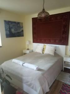 a bedroom with a large white bed with two tables at V4 Kilátóterasz Apartmanok Földszint in Nagymaros