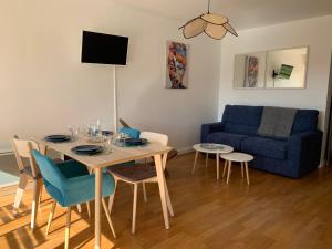 uma sala de estar com uma mesa e um sofá azul em Trouville, appartement rénové avec grande terrasse au calme em Trouville-sur-Mer