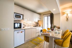 uma cozinha com armários brancos, uma mesa e cadeiras amarelas em KALAMAKİ FLATS em Kas