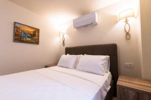 Schlafzimmer mit einem Bett mit weißer Bettwäsche in der Unterkunft KALAMAKİ FLATS in Kaş